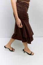 Brown ruched skirt worn by a person on a white background